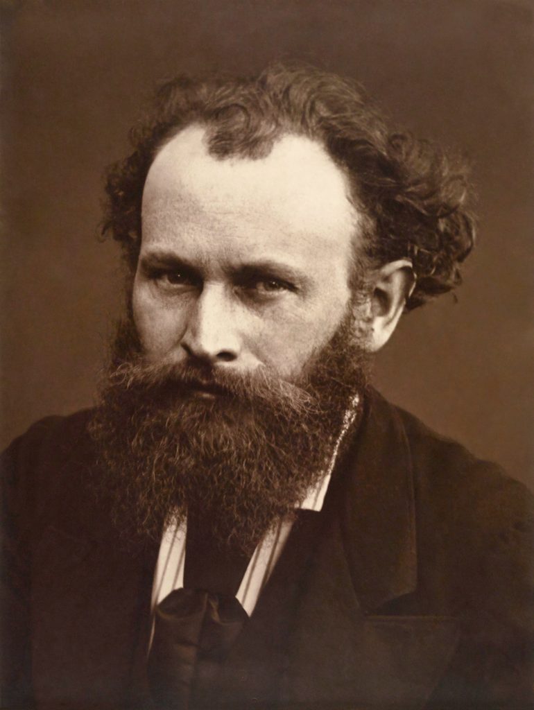 A close up photograph of manet, with a full beard and clad in a suit.