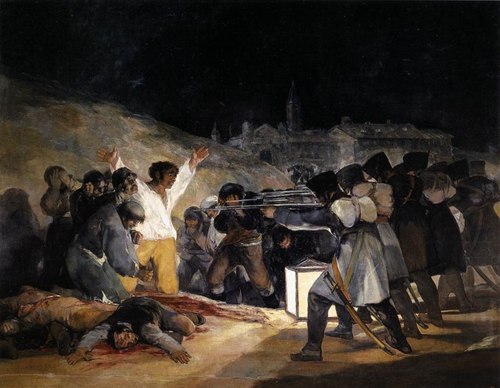 In the night, a group of soldiers fire upon a helpless crowd on the outskirts of a city. A man in a white shirt raises his arms upwards before the firing squad.