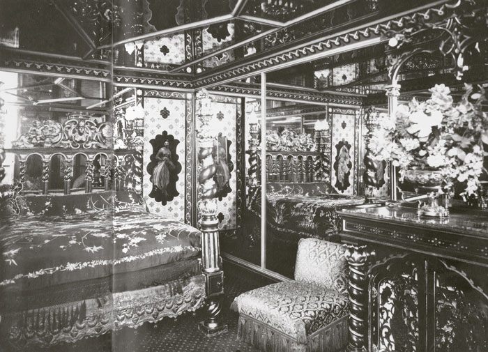 An opulent bedroom filled with lavish walls, mirrors and a venus statuette.