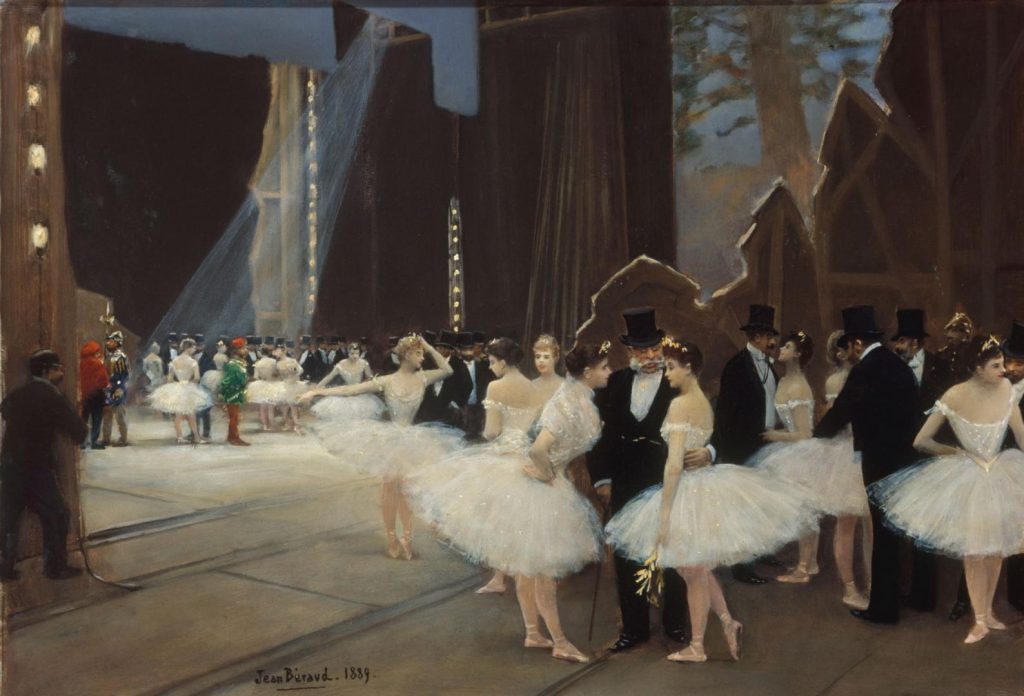 Backstage at a ballet performance, older aristocratic men in black suits mix with ballet performers. From this angle, we see the back of the decor and the stagelights.