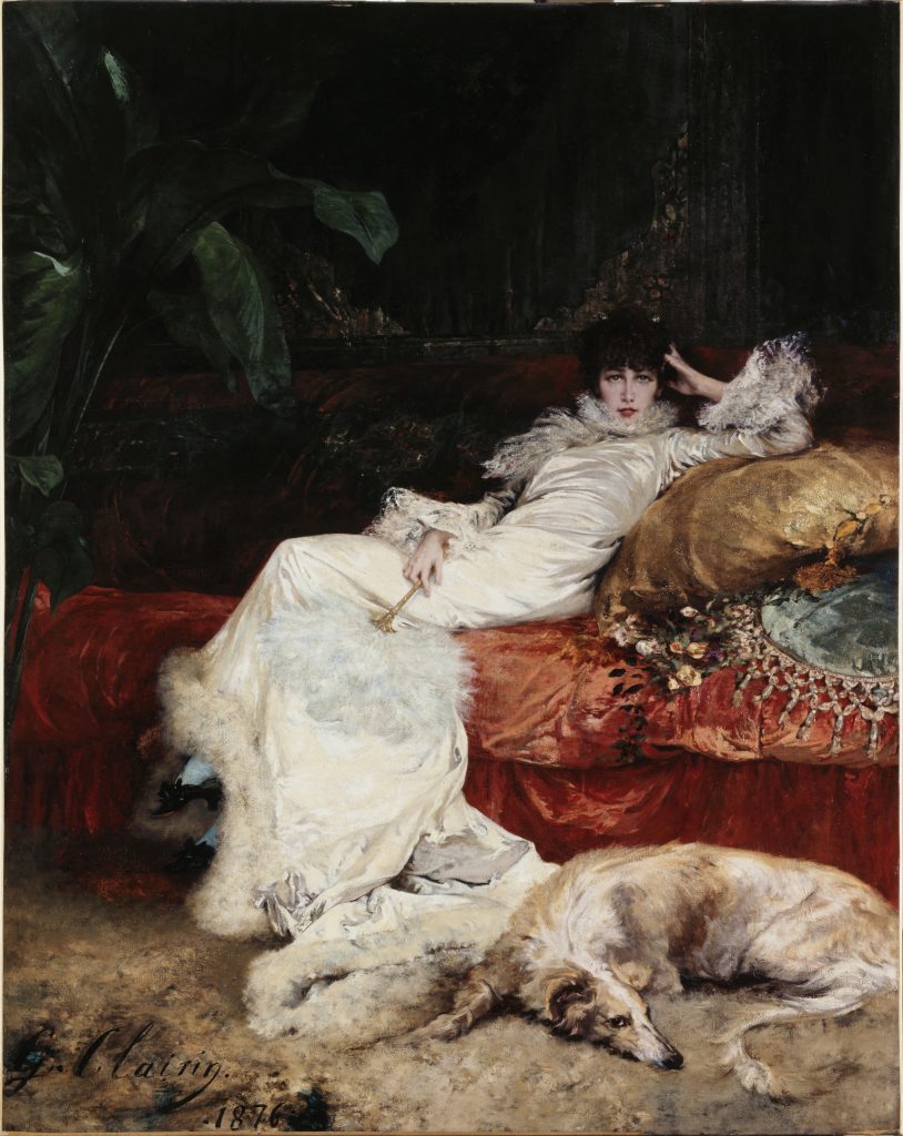A black-haired severe courtisan in a long white dress leans on an eccentric and vibrant set of bedsheets. A white wolfhound lays on the ground by her feet.