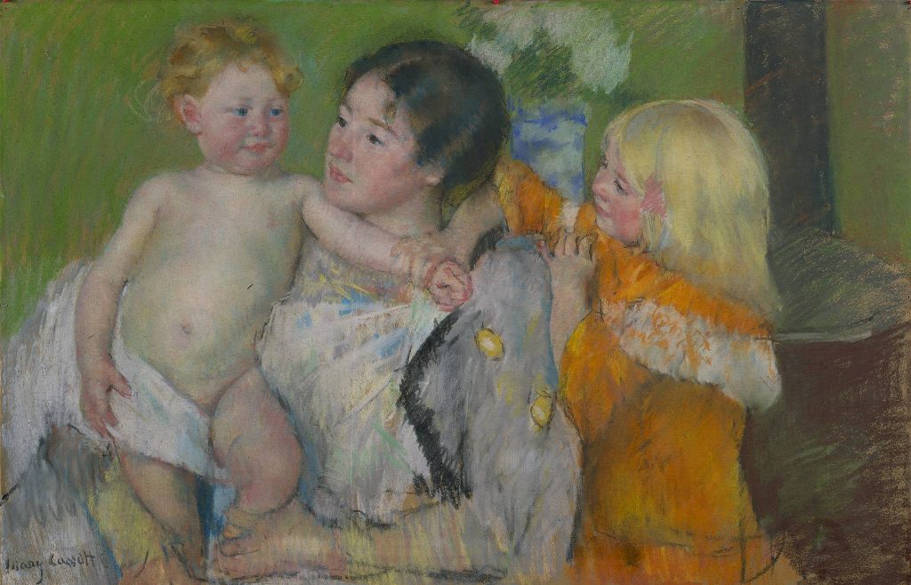 A mother is flanked by two of her children, one she dries with a towel. Both children have blonde hair, the mother is brunette.