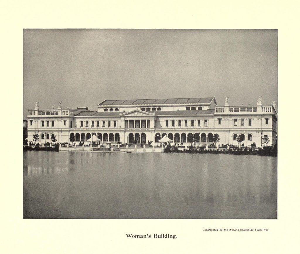 A photograph of a wide neo-classical building in front of a lake. It has a terasse and is beset by statues, underneath is written: Woman's Building.