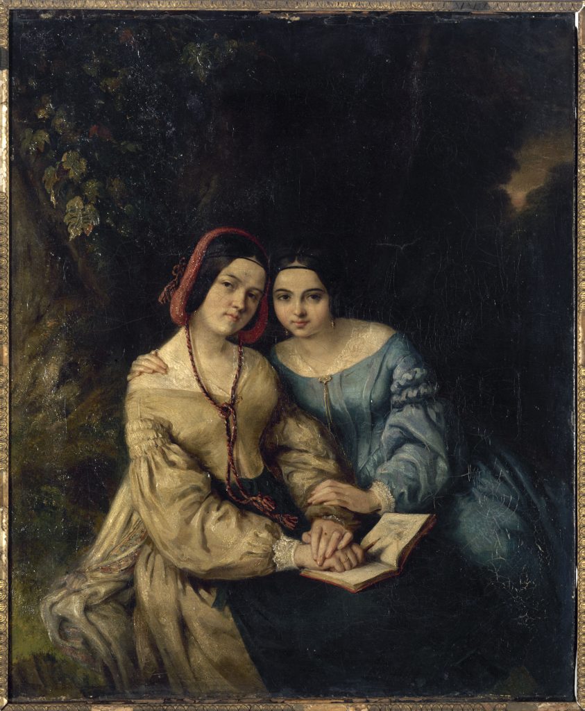 Before a dark flowered beckground, two women look forward with a book set on their laps. The woman to the right leans on the other, almost in embrace.