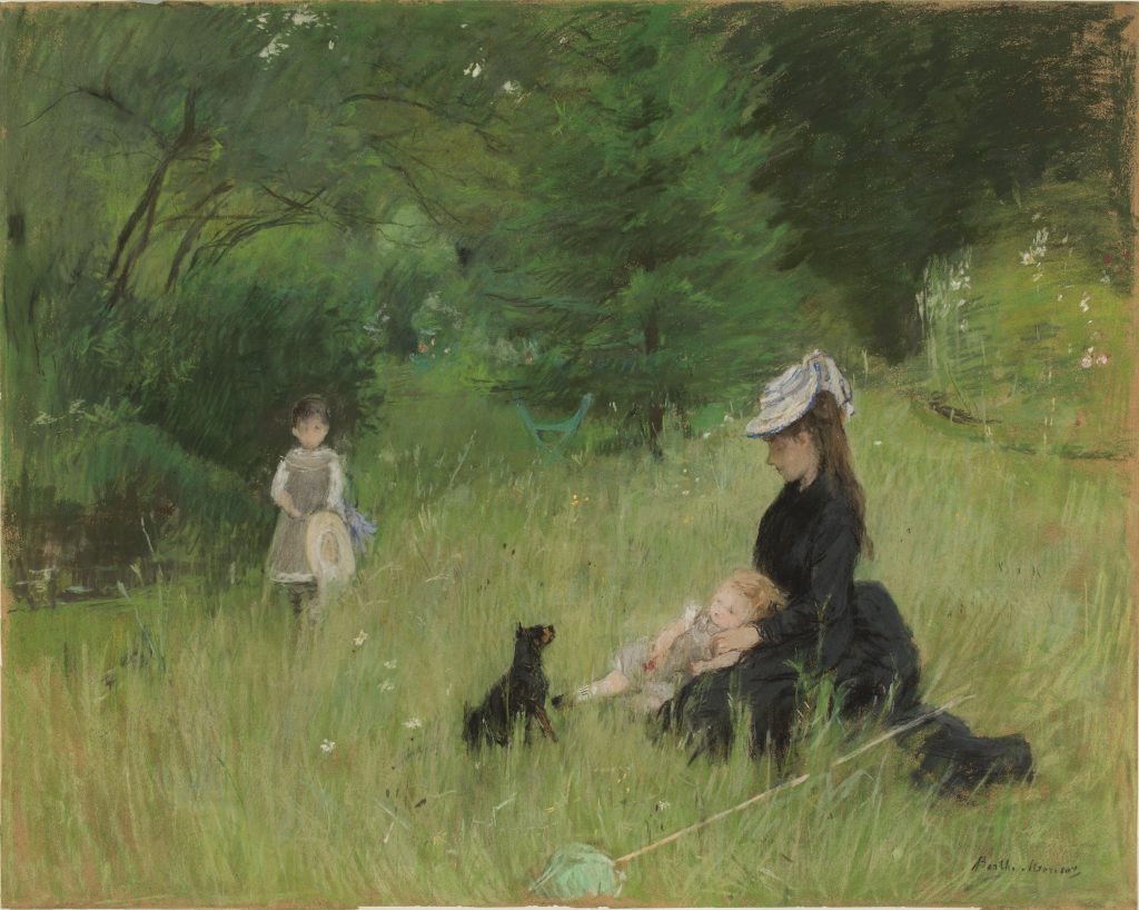 A family; composed of a woman, her two daughters, and a dog, are sat around a grassy park setting. The mother wears black, the daughers in pinkish whites.