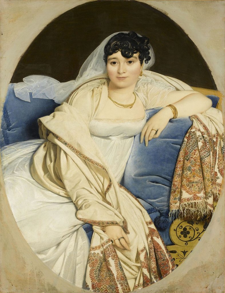 A simply but glowing portrait of a woman, in a decadent golden-white dress, reclining on a blue sofa. She wears a veil pushed behind her hair.