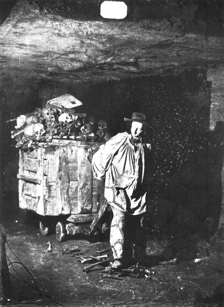 Somber photo of an undertaker pulling a cart of human remains in the Paris underground.