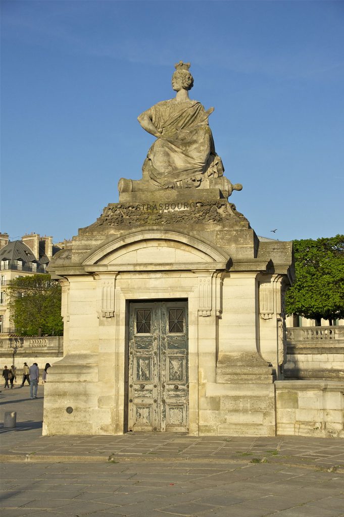 A photograph of the statue of Strasbourg, where a royal figure seems to emerge from a tomb.