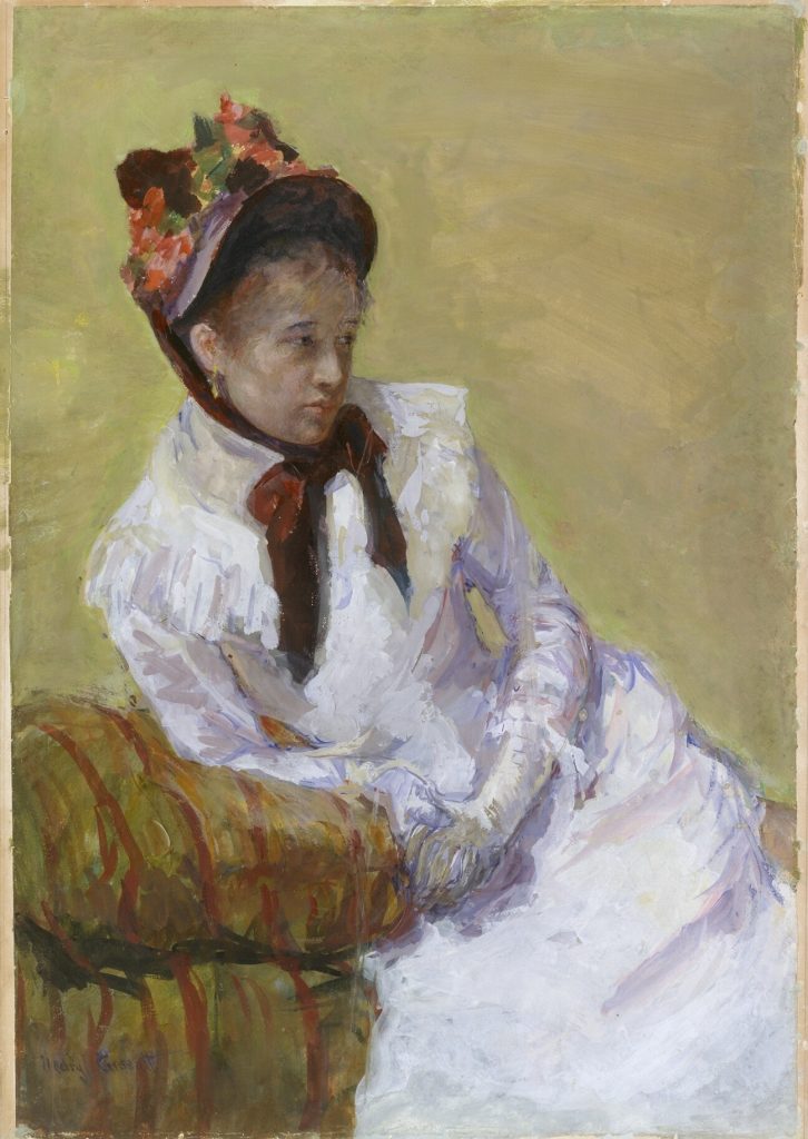 A stoic woman, clad in a white dress and a flowery bergère hat, leans on a sofa before a yellow background.
