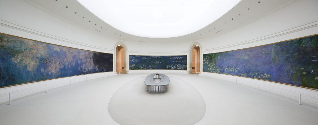 A parisian exhibition of Monet's wide pond landscapes hung around a circular white exhibition room.