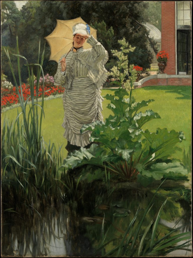 A portrait of a woman in a striped dress before a garden. Behind her is a brick estate.