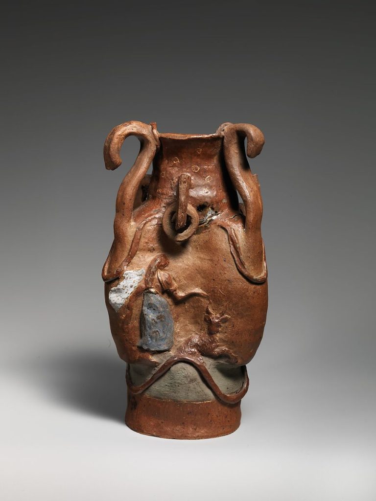 An animalistic brown stoneware vase with fauna embedded into it's body. The handles curve upwards.
