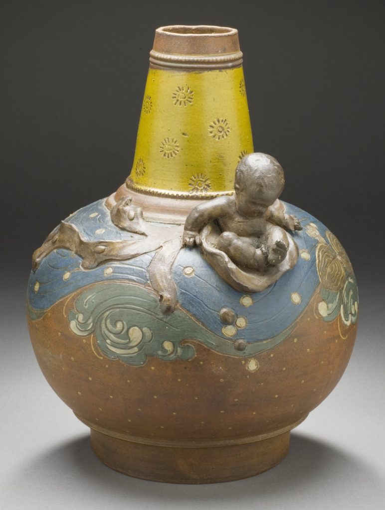 A colourful ceramic vase sprouting a cherubic sculpture of an enfant from it's body.