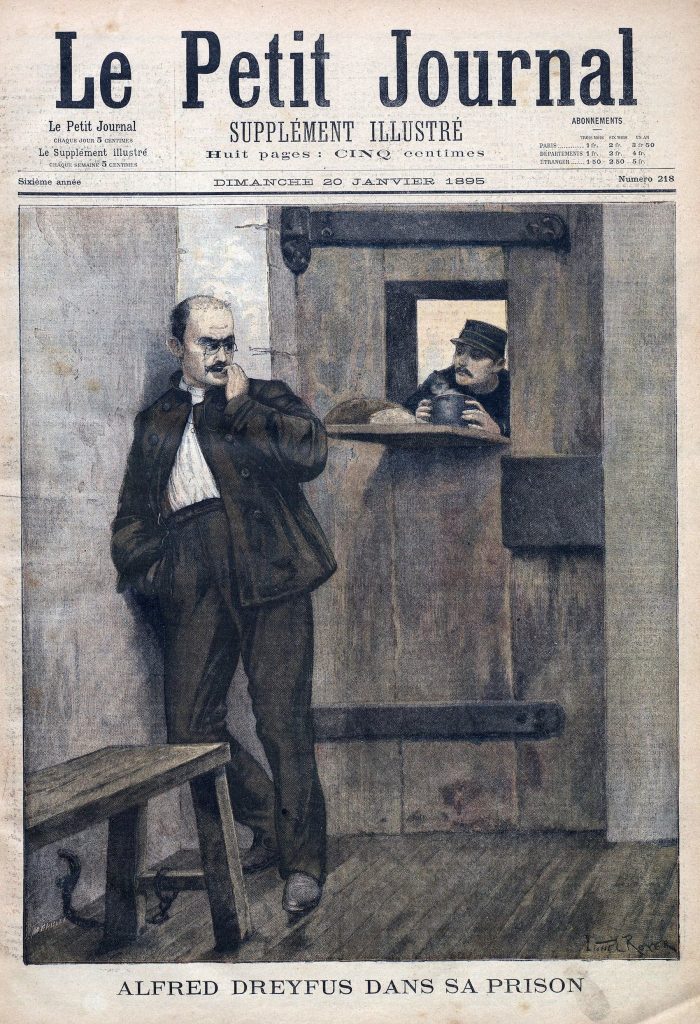 A print journal cover depicting Drefus standing in his prison cell, a conniving expression on his face and his back to a prison guard serving food.