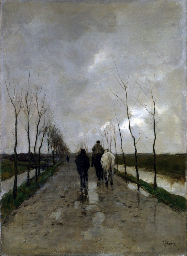 A rider, accompanied by two rider-less horses, head down a muddy road under cloudy conditions.