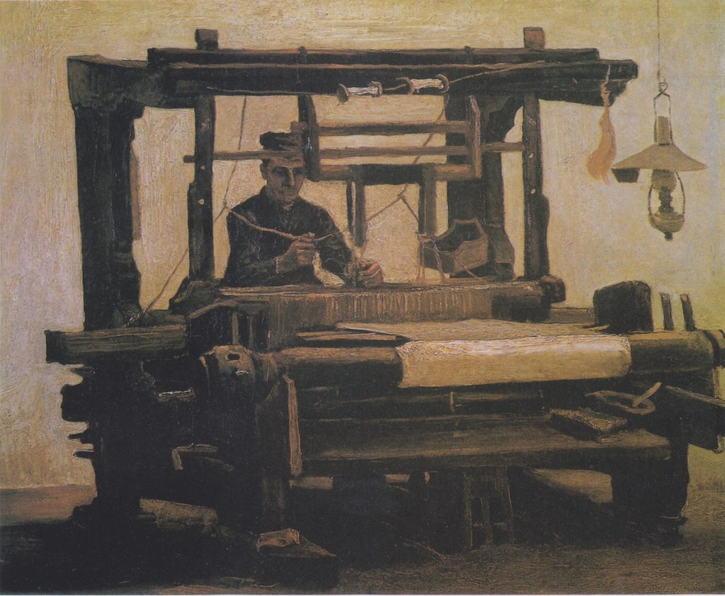 A uniformed man sits at a weaving station, by lamp-light.
