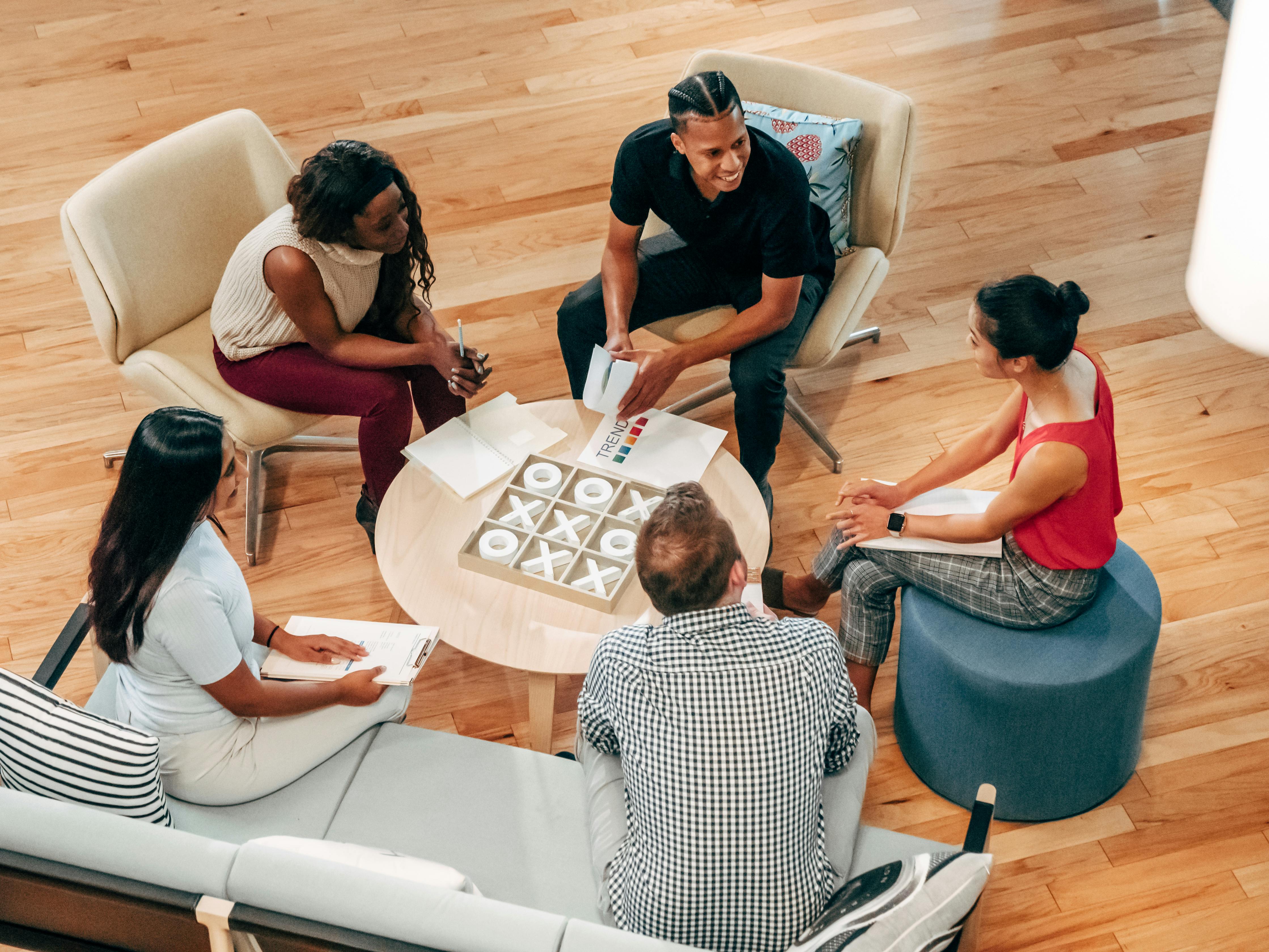 A group of people seated on a couch and chairs having a friendly discussion