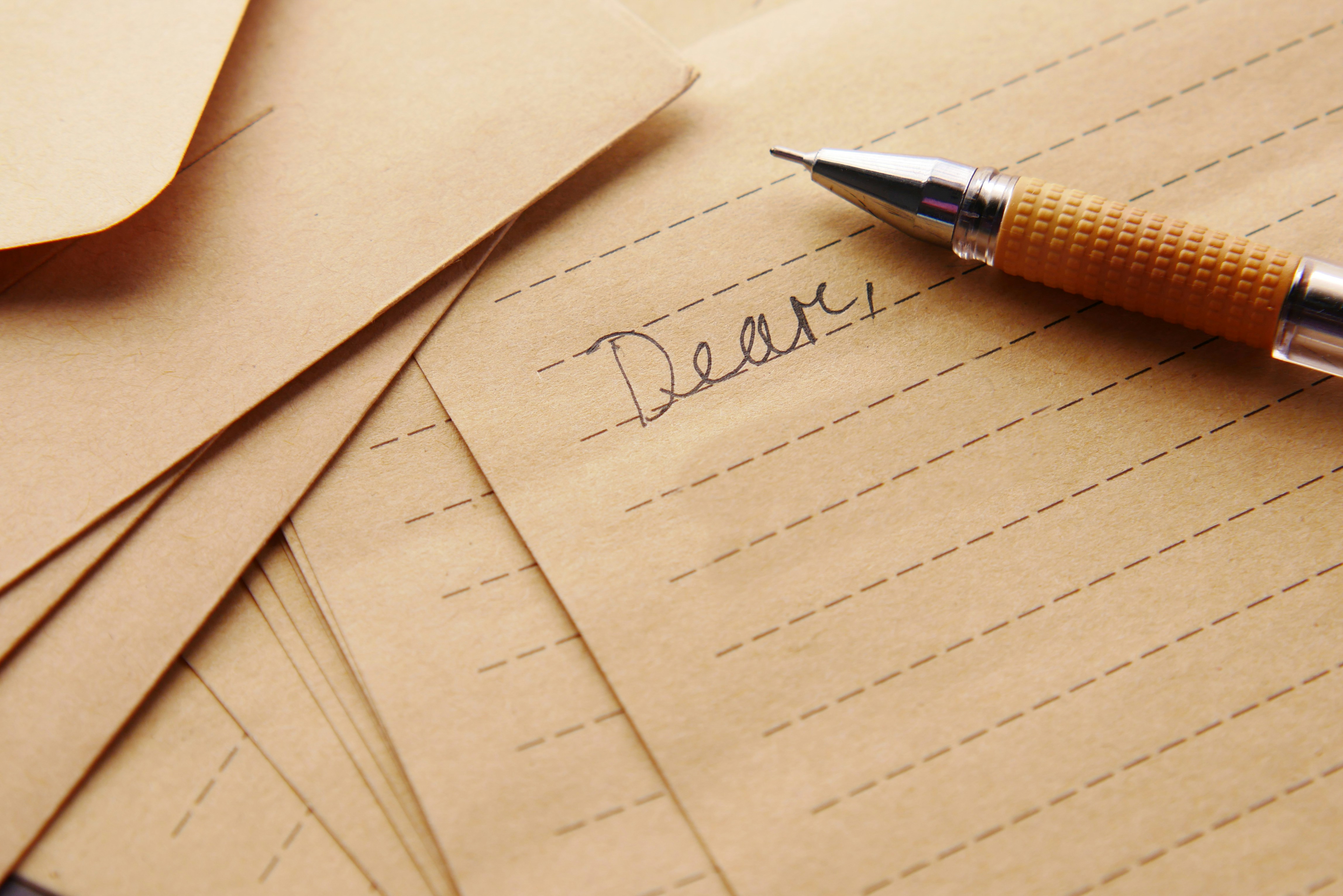 Tan lined paper with a mechanical pencil. "Dear.." is written in cursive.