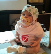 Baby wearing a stretchy cap that contains many small sensors or electrodes