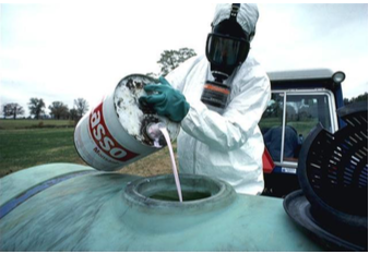 Man wearing a protective mask and gloves pouring hazardous white liquid into a large green bucket