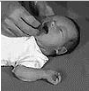 Black and white photo of a hand touching the cheek of a baby having their mouth open