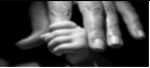 Black and white photo of a baby's hand holding an adult finger