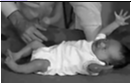Infant spreading out their arms and legs while laying down on their back