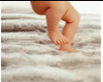 Baby's legs moving in stepping-like motion while touching a soft surface