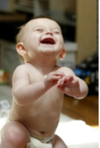 Baby smiling with the mouth open and eyes closed while almost standing up