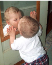 Young infant kissing his reflection in the mirror