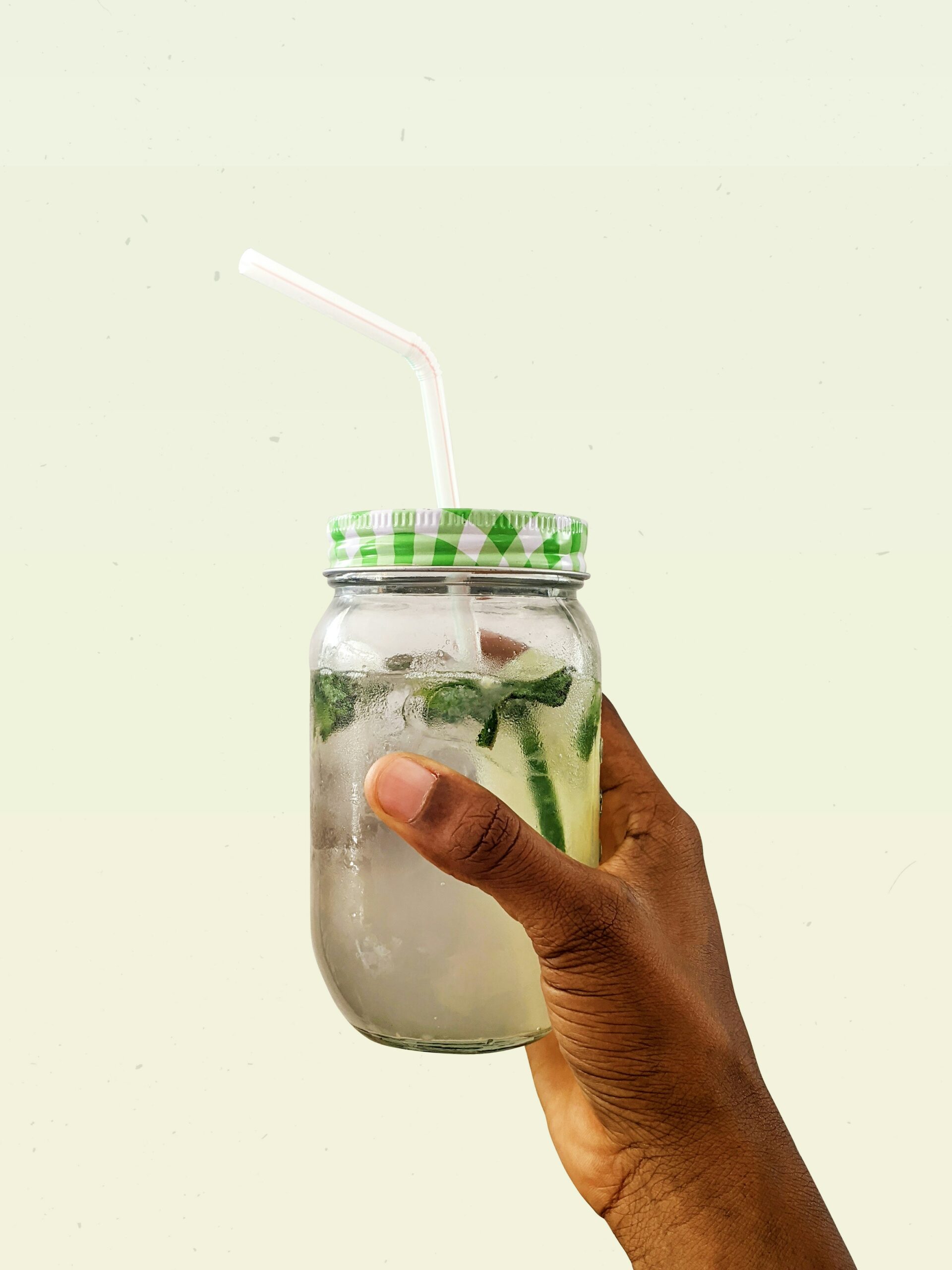 A hand holding a glass jar with a straw. A hand holding a glass jar with a straw.