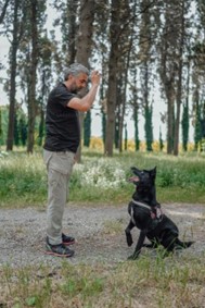 A man standing next to a black dog on top of a field