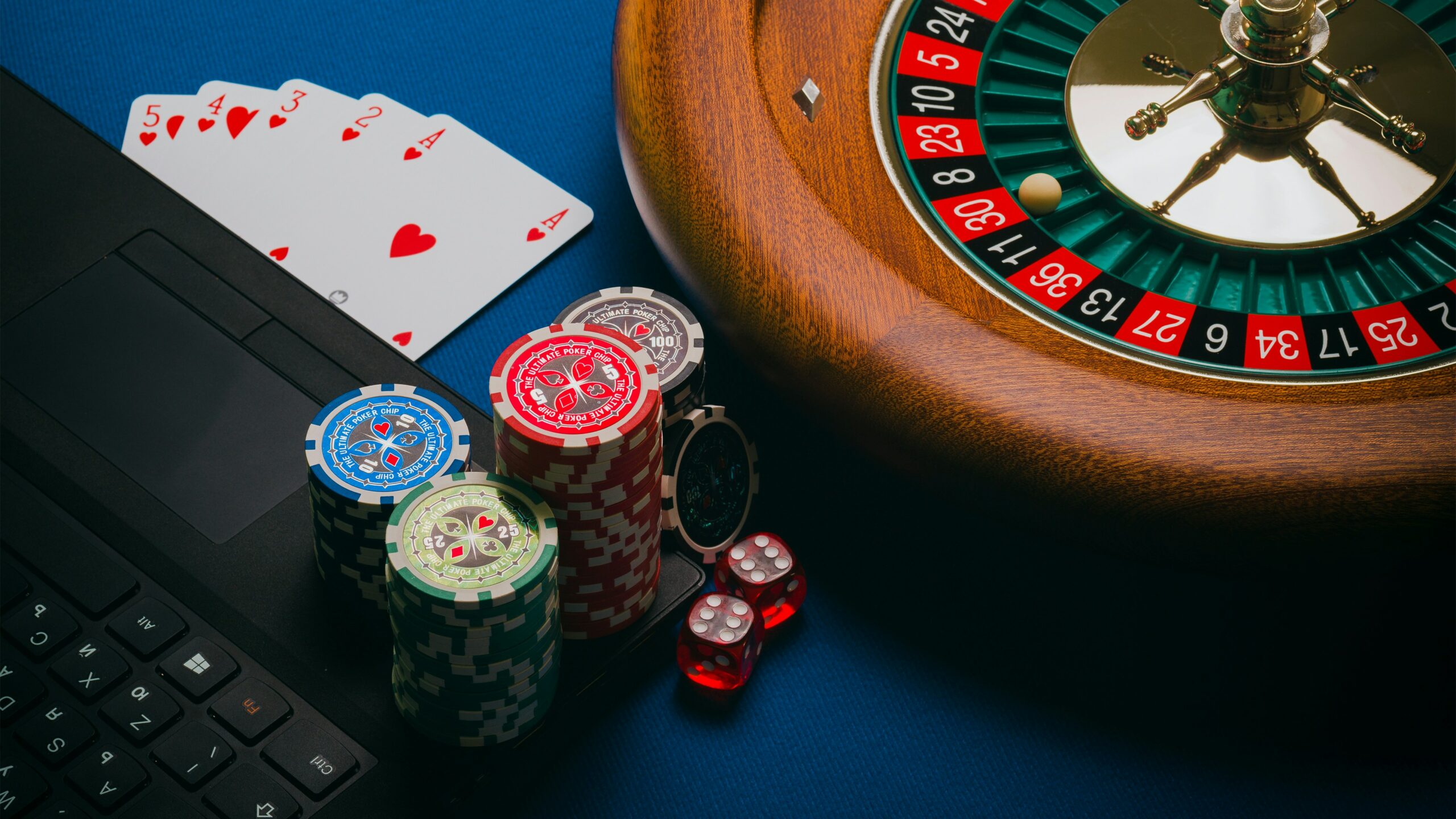 Cards and poker chips on a table with a roulette wheel.