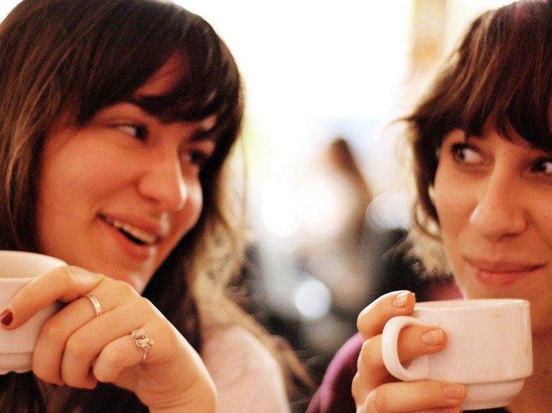 A picture depicting two friends having a conversation over coffee.