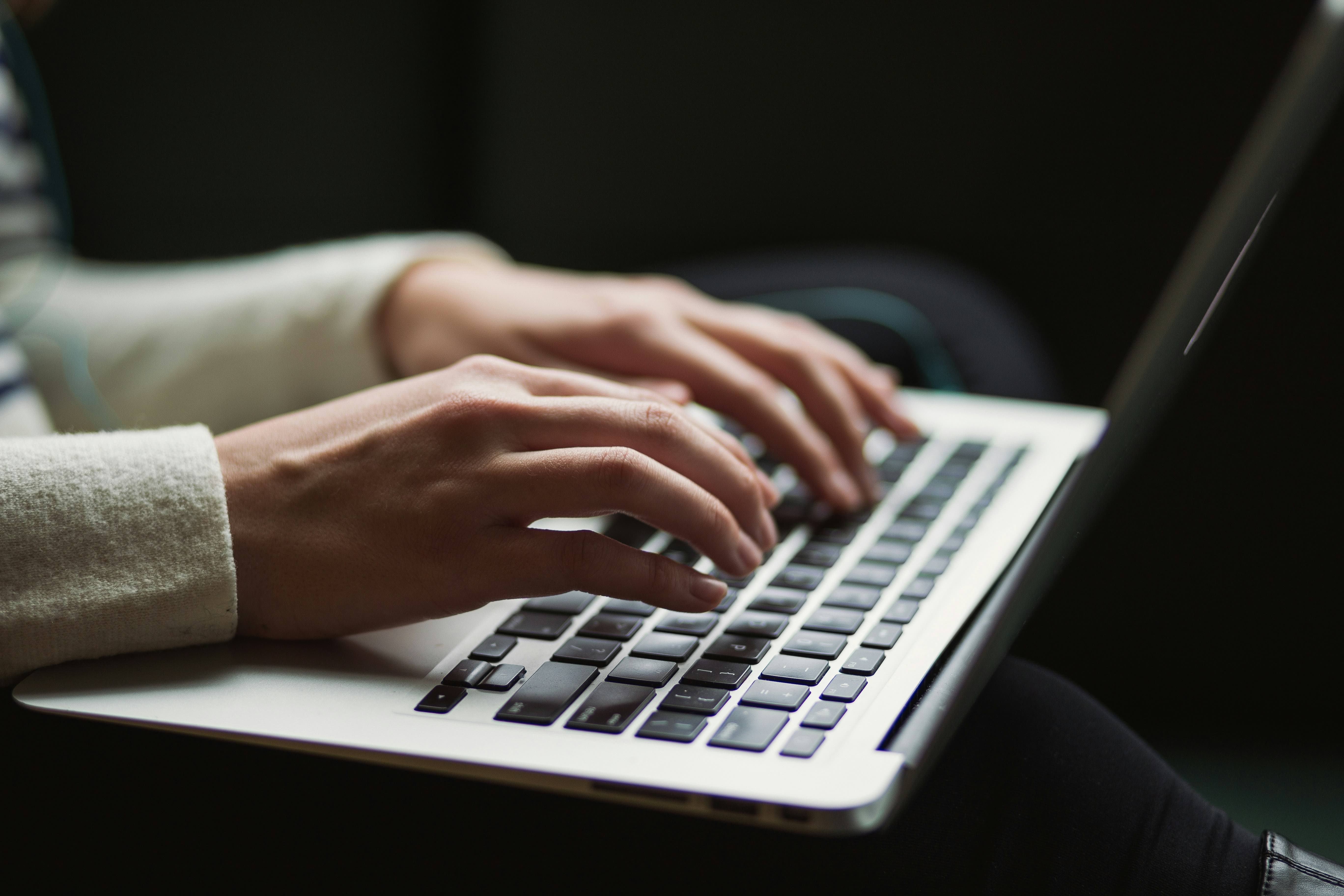 Photo of hands typing on a laptop.