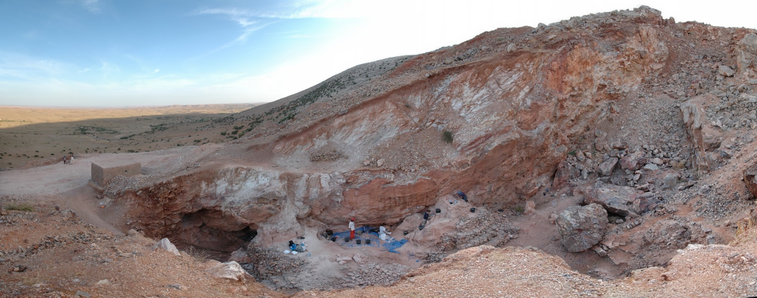 Rocky hillside with exposed layers. People are visible at the base.