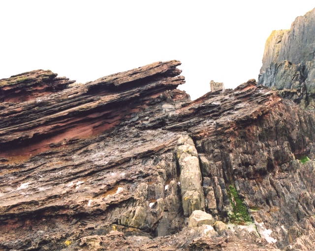 Horizontal layers of rock rest on vertical layers of rock.