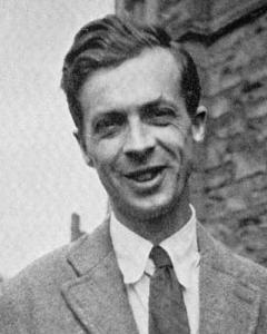 Black-and-white photo of smiling person in a suit and tie in front of a building.