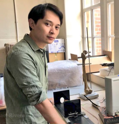 A man with short black hair and brown eyes, looks at the camera. 