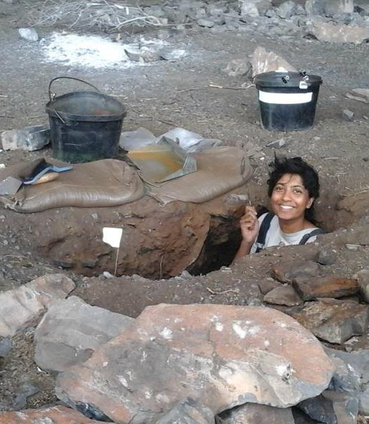 A woman with black hair stands in a hole in the ground.