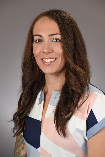 A woman with long brown hair smiles at the camera.