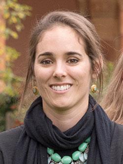 A woman with straight brown hair pulled back smiles at the camera. 