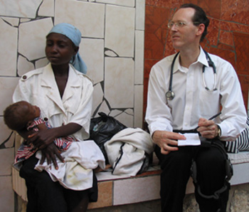 Doctor takes notes sitting next to a woman and a sick toddler.