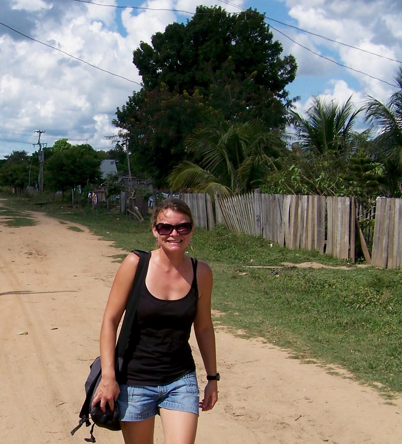 A woman walks on an unpaved street.